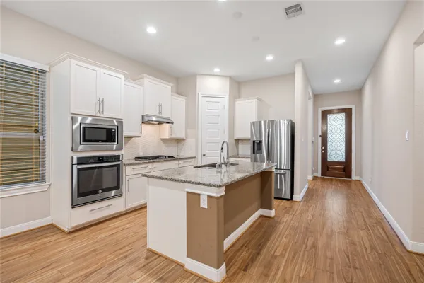 a kitchen with stainless steel appliances kitchen island granite countertop a stove and a refrigerator