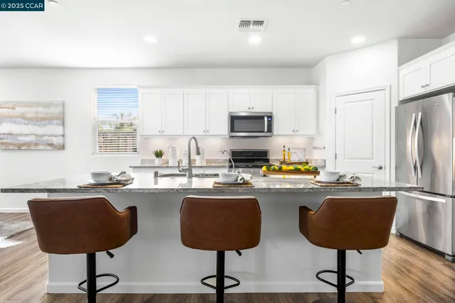 a kitchen with a sink a stove a refrigerator cabinets and dining table