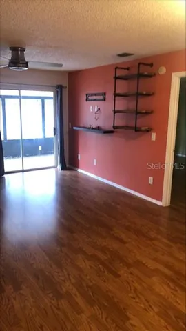 an empty room with wooden floor chandelier fan and windows
