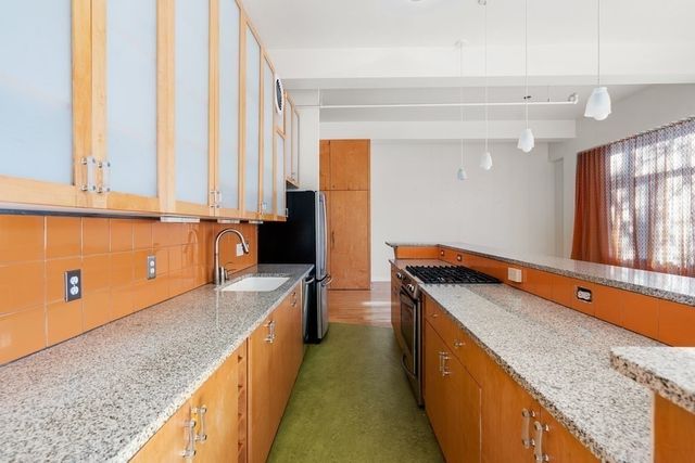a kitchen with stainless steel appliances granite countertop a sink and a refrigerator