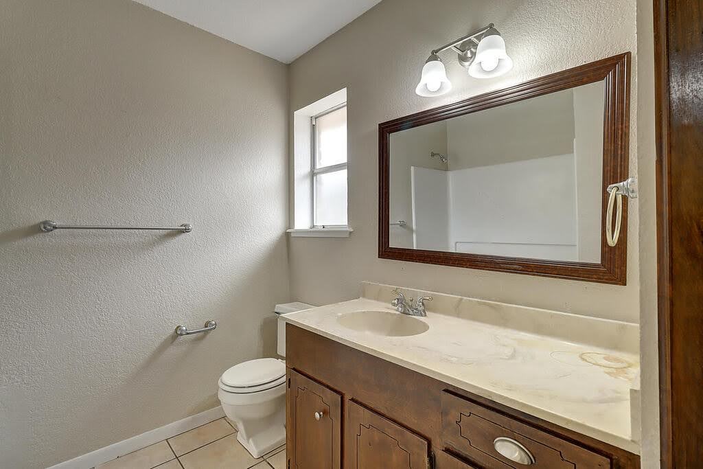 5225 Bonham Street Corpus Christi, TX 78415 - Photo 28 of 40 a bathroom with a toilet a sink a vanity and mirror