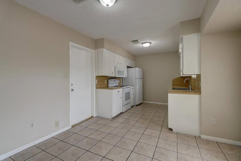 5225 Bonham Street Corpus Christi, TX 78415 - Photo 10 of 40 a kitchen with a refrigerator and white cabinets