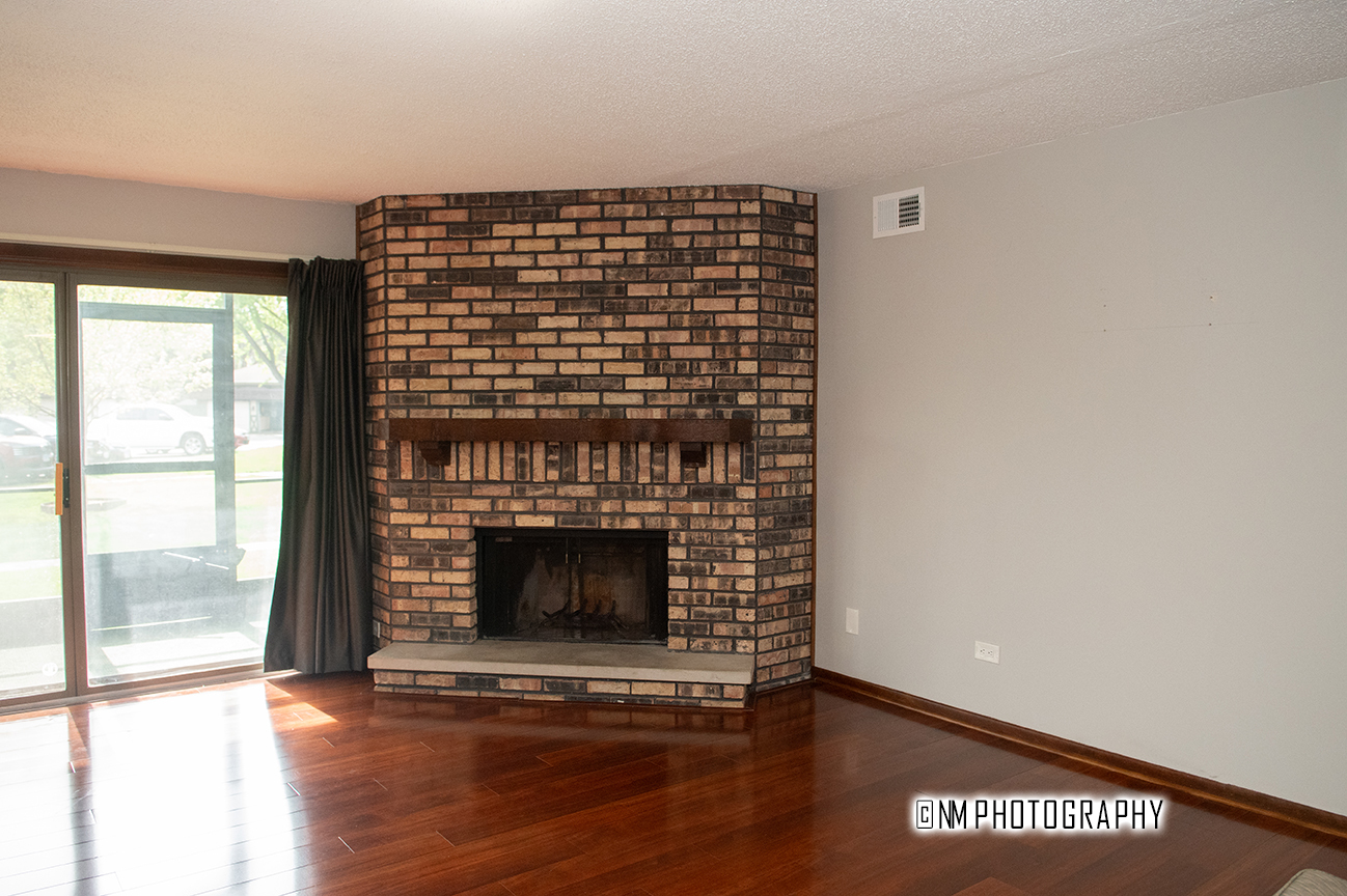9182 S Road, Unit A Palos Hills, IL 60465 - Photo 2 of 16 a view of an empty room with wooden floor and a fireplace