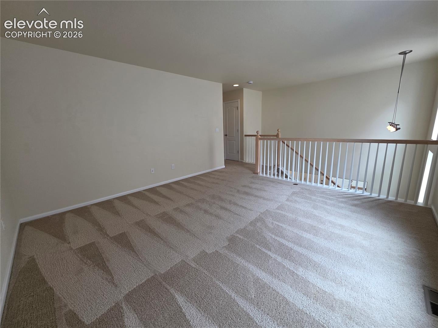 874 Diamond Rim Drive Colorado Springs, CO 80921 - Photo 12 of 28 Expansive carpeted area featuring a light fixture, painted walls, and a wood handrail with white balusters