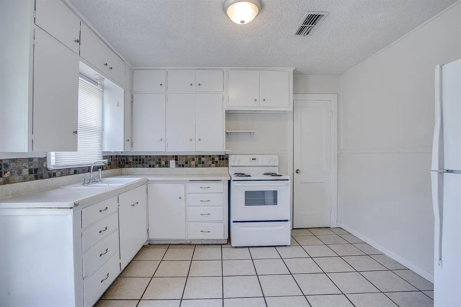 2708 33rd Street Lubbock, TX 79410 - Photo 4 of 12 a kitchen with white cabinets and appliances