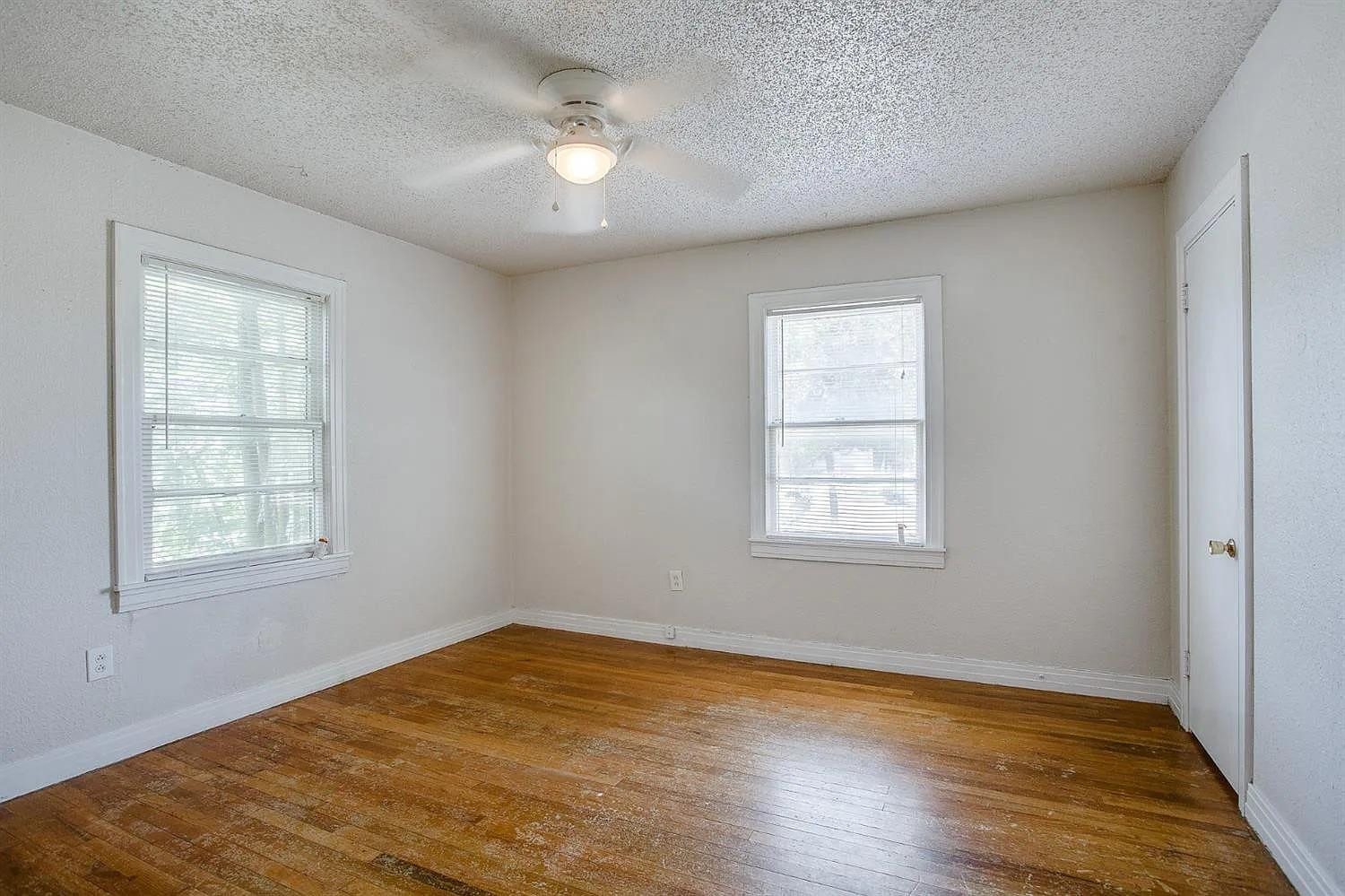 2708 33rd Street Lubbock, TX 79410 - Photo 8 of 12 an empty room with wooden floor cabinet and windows
