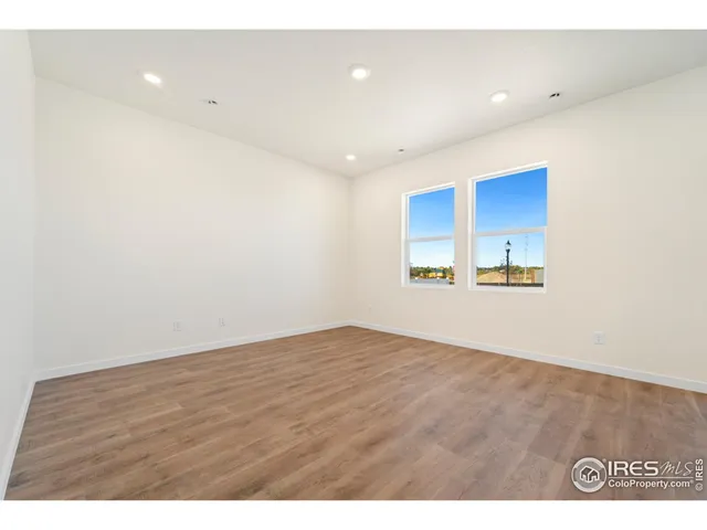 a view of kitchen and empty room with wooden floor