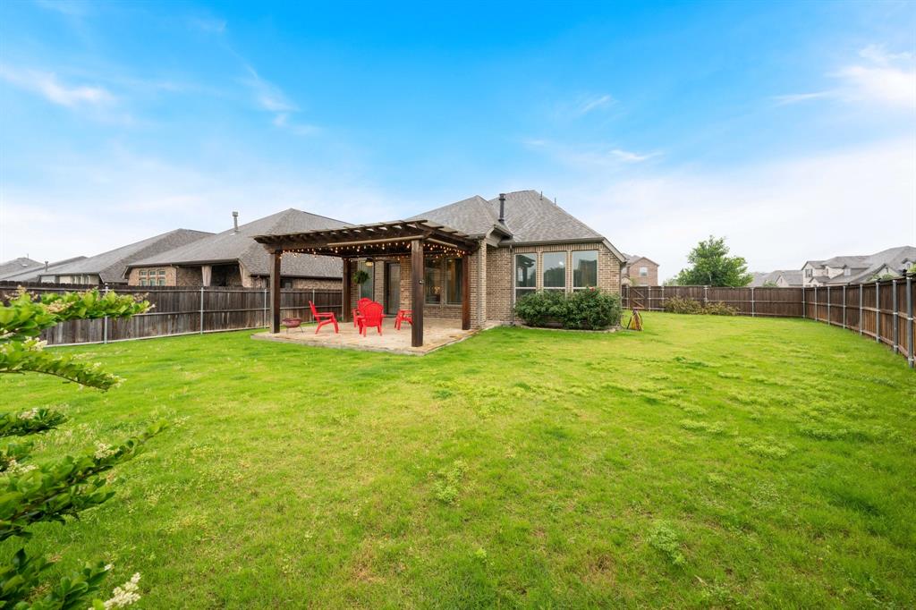 1501 Calcot Lane Forney, TX 75126 - Photo 29 of 34 Spacious fenced backyard featuring a wood pergola over a patio area, brick exterior, and multiple windows