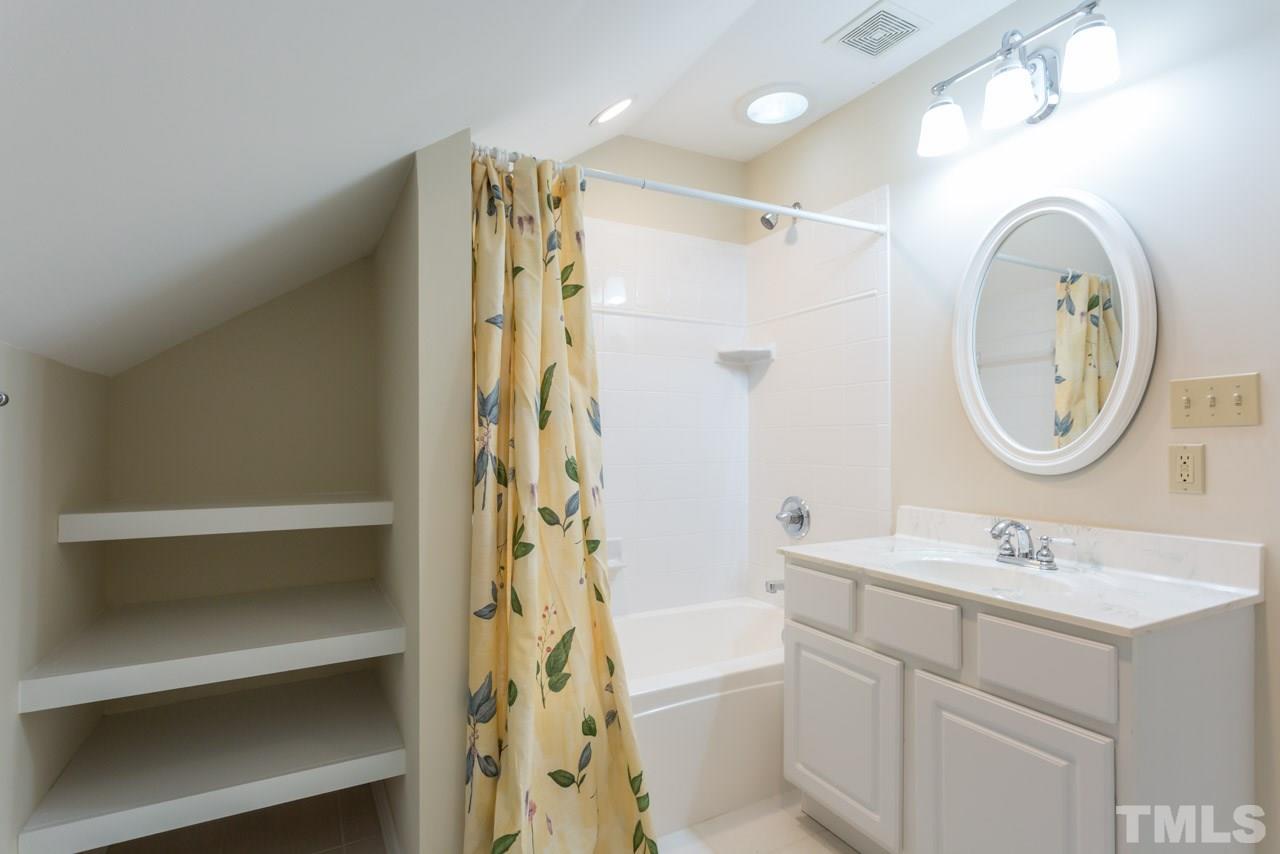 2909 Patrie Place Raleigh, NC 27613 - Photo 22 of 25 a bathroom with a sink mirror vanity and a shower