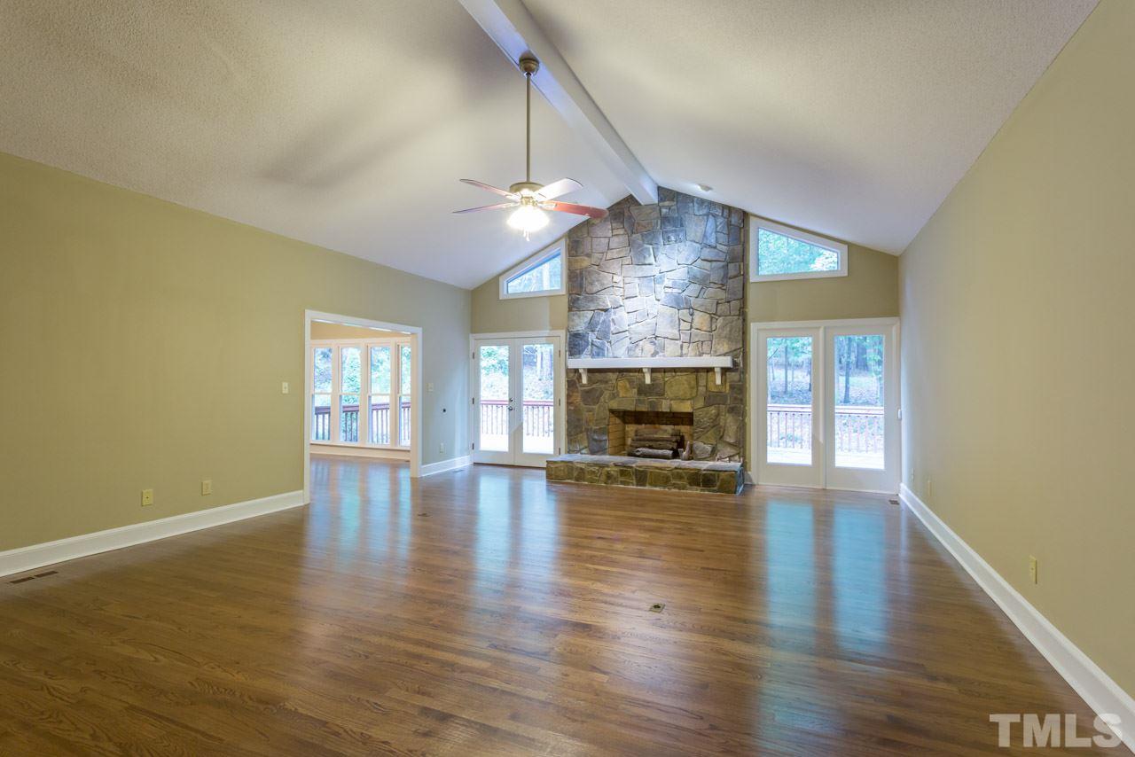 2909 Patrie Place Raleigh, NC 27613 - Photo 4 of 25 an empty room with wooden floor fireplace and windows