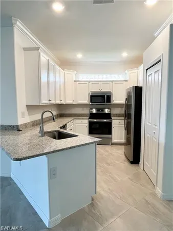 a kitchen with kitchen island granite countertop a refrigerator and a sink