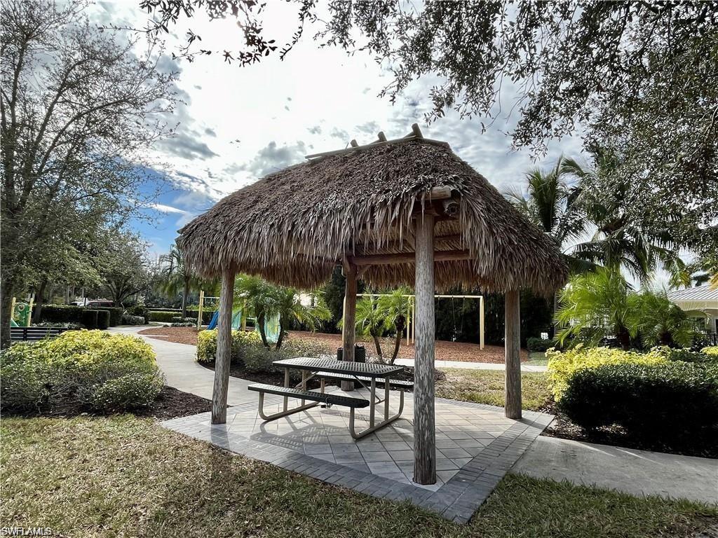 2057 Tamarron Lane Naples, FL 34120 - Photo 23 of 27 a view of a patio with a table and chairs under an umbrella