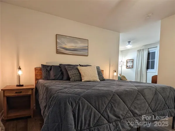 a bedroom with a bed and a lamp on dresser