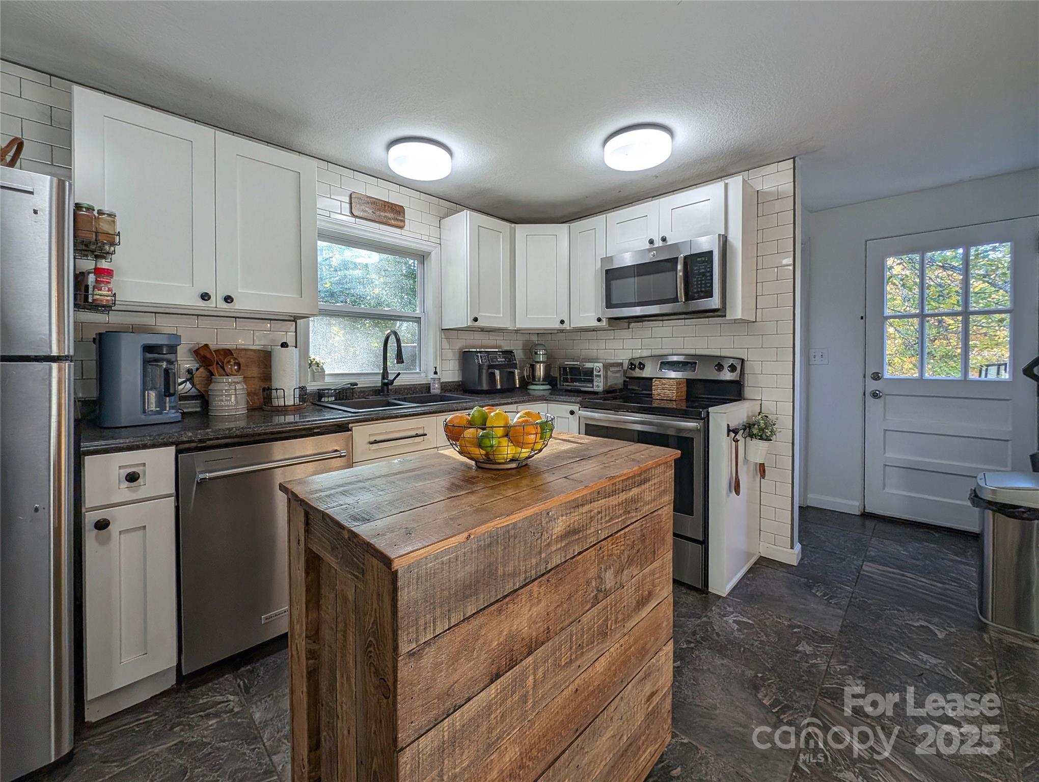 317 Balsam Drive Waynesville, NC 28786 - Photo 4 of 45 a kitchen with a stove a sink a refrigerator a window and cabinets