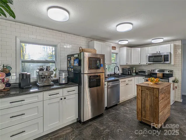 a kitchen with granite countertop white cabinets and stainless steel appliances