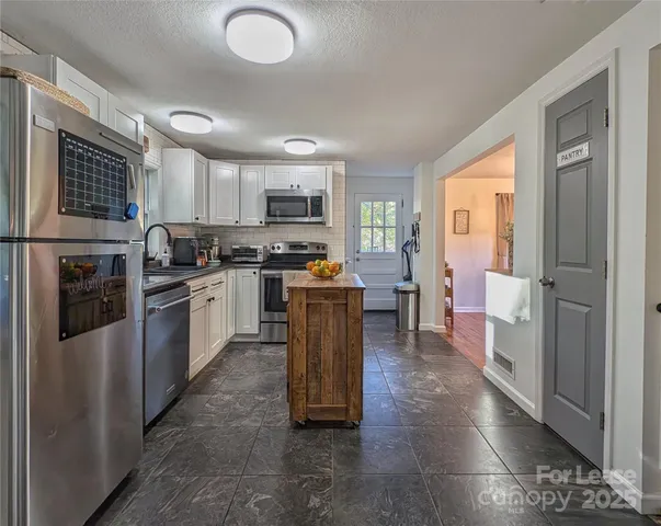 a kitchen with stainless steel appliances granite countertop a stove a sink dishwasher a refrigerator and a microwave