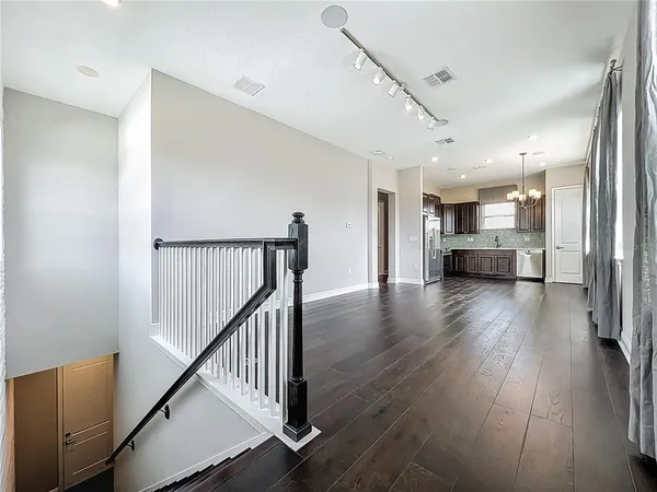 a view of a hallway with wooden floor and kitchen