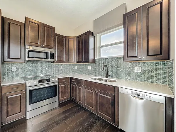 a kitchen with stainless steel appliances granite countertop a sink stove microwave and refrigerator