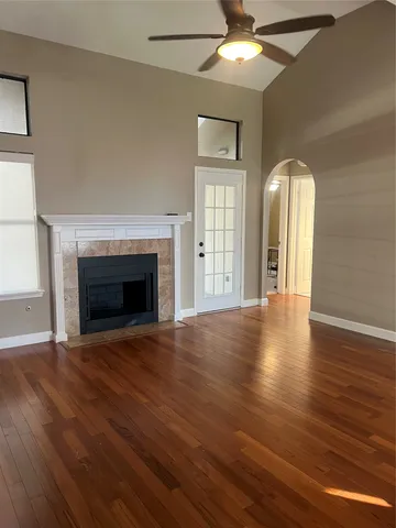 an empty room with wooden floor fireplace and windows