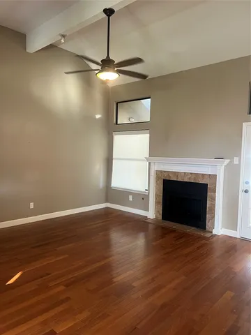 a view of an empty room with wooden floor fireplace and a window