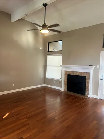 a view of an empty room with wooden floor fireplace and a window