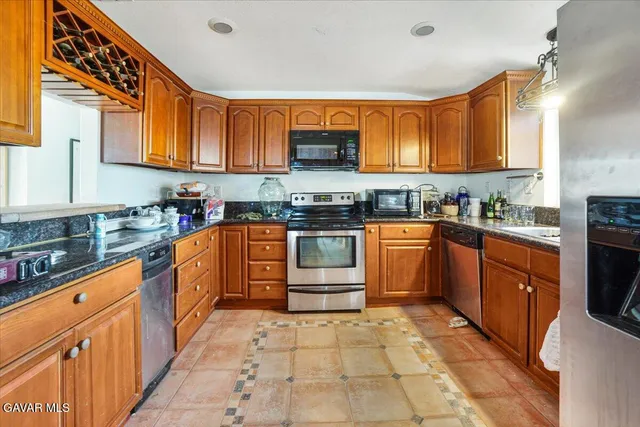a kitchen with stainless steel appliances granite countertop wooden cabinets and a counter top space