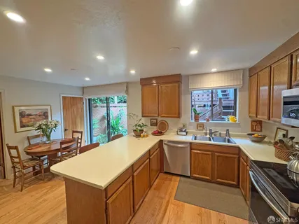 a large kitchen with a large counter top space a sink stainless steel appliances and cabinets