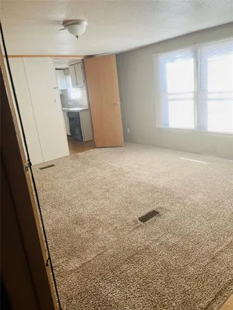 a view of empty room with window and refrigerator