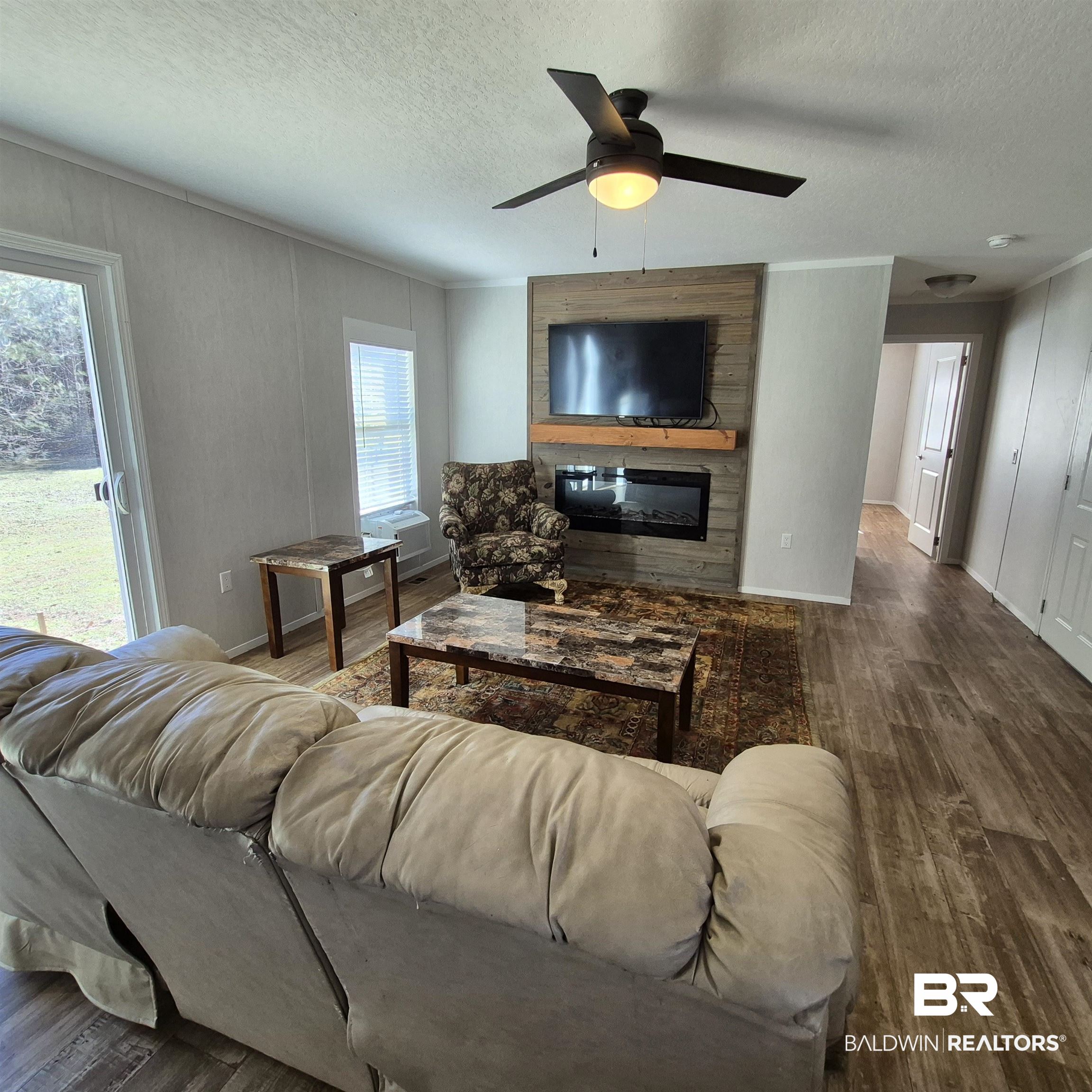 8867 Old Stage Road Repton, AL 36475 - Photo 3 of 37 Living area featuring a fireplace, wood finished floors, a textured ceiling, and a ceiling fan