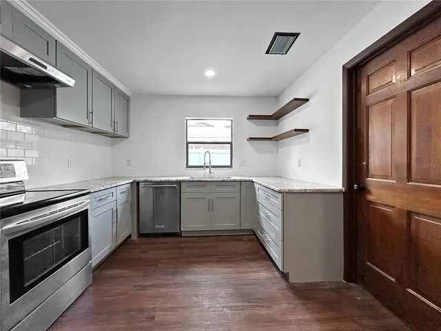 a kitchen with granite countertop a sink cabinets and stainless steel appliances