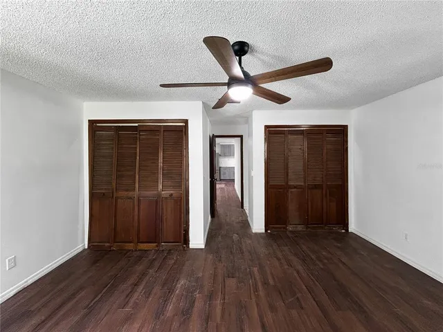 a view of a hallway with wooden floor and a ceiling fan
