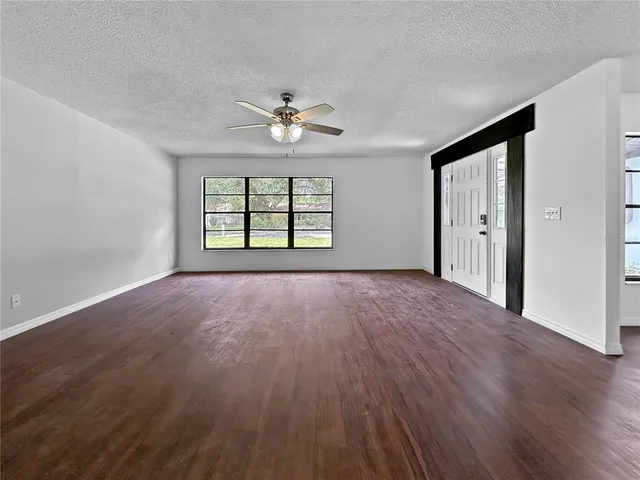 a view of an empty room with a window and wooden floor