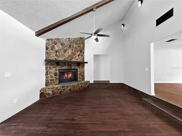 a view of an empty room with wooden floor fireplace and a window