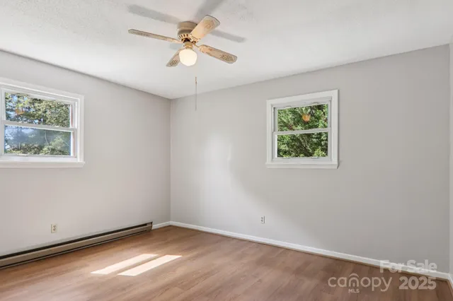 an empty room with wooden floor and ceiling fan