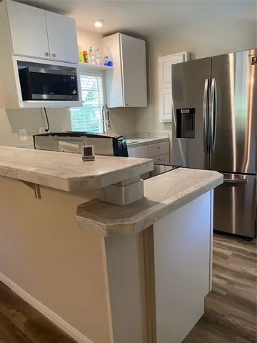 a kitchen with stainless steel appliances a sink a stove a microwave a refrigerator and cabinets