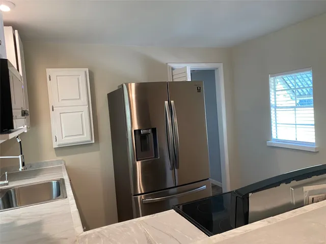 a kitchen with granite countertop a refrigerator and a sink