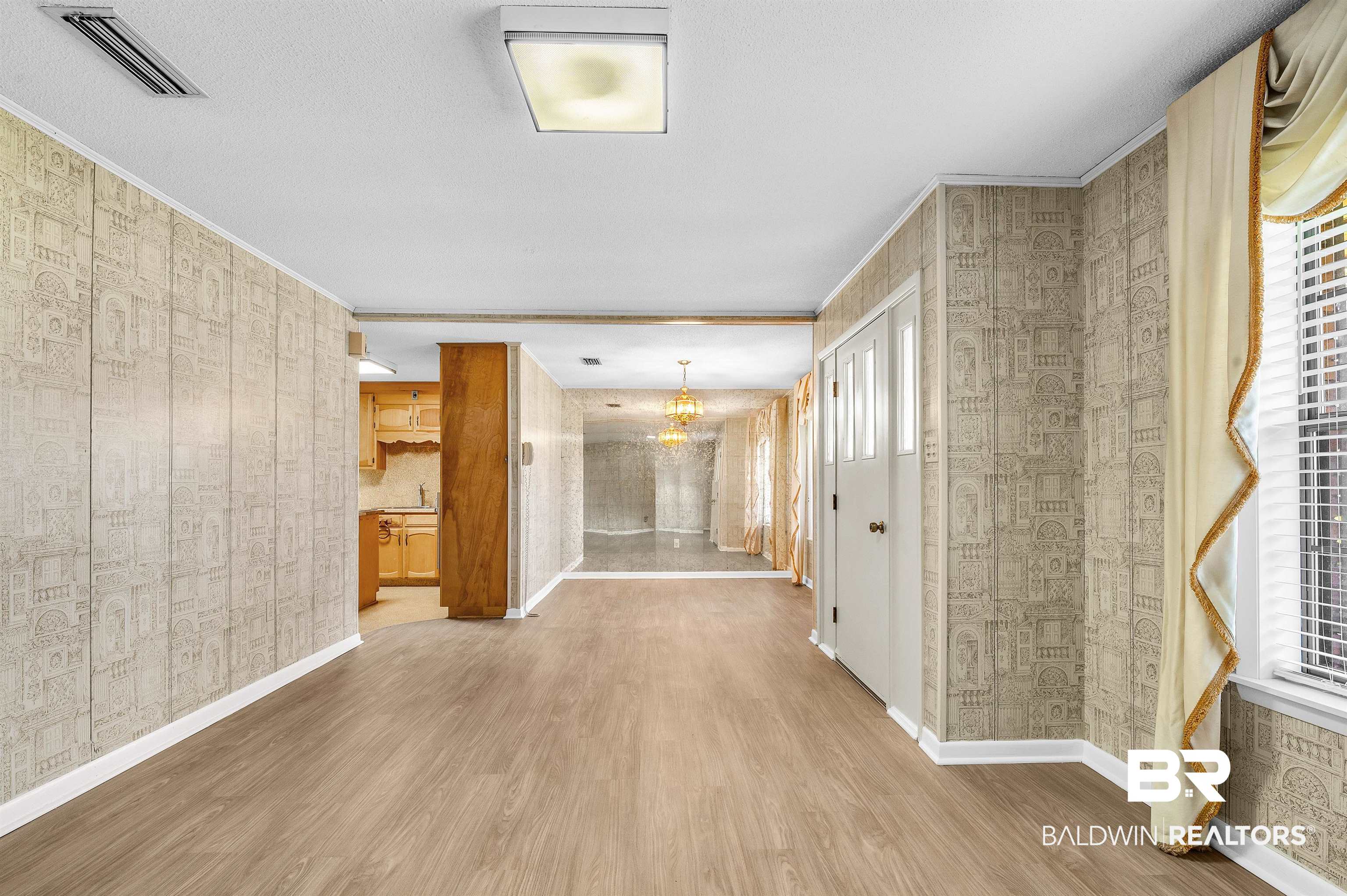 610 East Walker Avenue Foley, AL 36535 - Photo 13 of 38 Unfurnished living room featuring wood finished floors, crown molding, a chandelier, plenty of natural light, and wallpapered walls