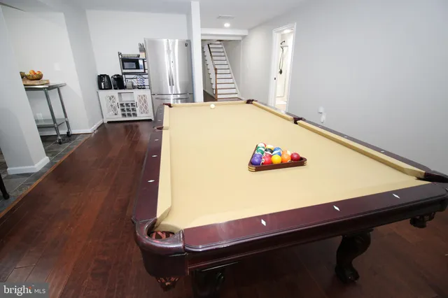 a view of kitchen with stainless steel appliances granite countertop a refrigerator a stove and a dining table with wooden floor