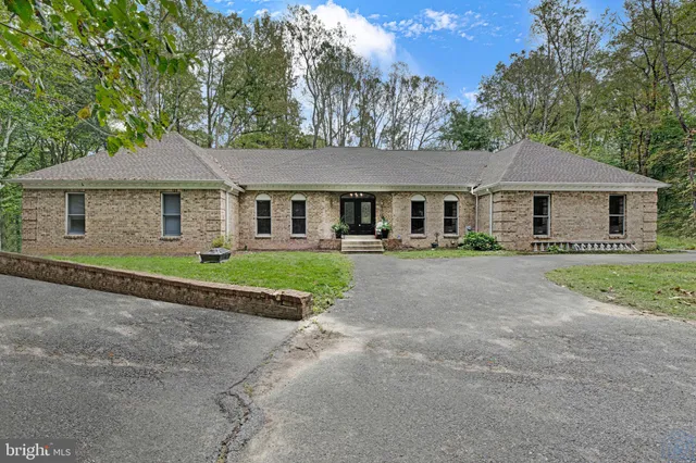 a front view of a house with a garden and trees