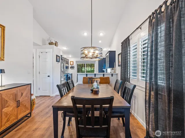 a kitchen with stainless steel appliances granite countertop a stove a refrigerator a sink dishwasher with a dining table and chairs with wooden floor