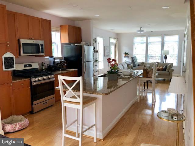 a kitchen with stainless steel appliances kitchen island granite countertop a stove refrigerator and microwave