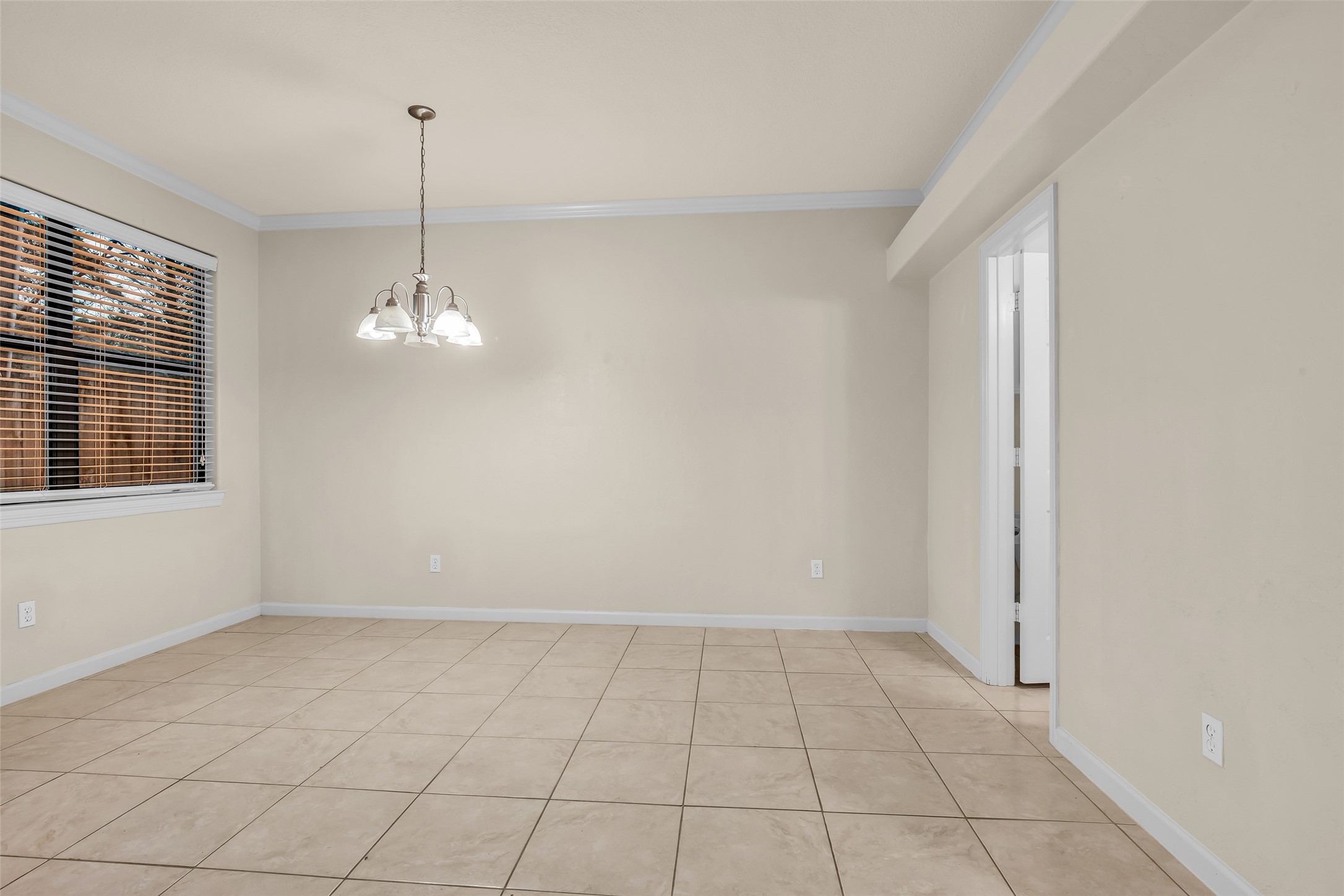 1898 Longmire Road, Unit 5 Conroe, TX 77304 - Photo 25 of 48 Bright dining area with neutral tile flooring, soft beige walls, and a modern chandelier. Large window with blinds offers natural light.