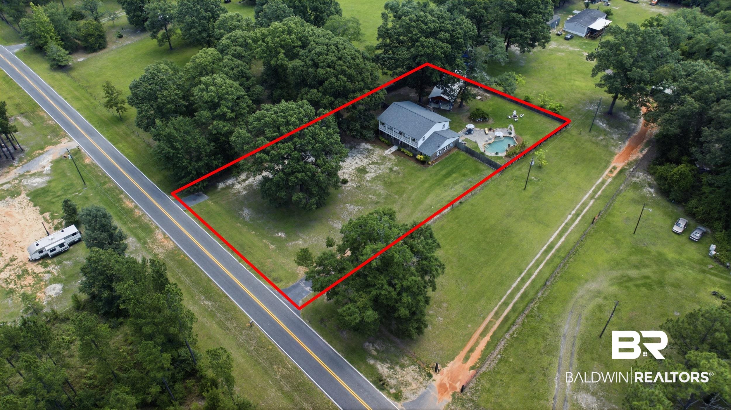 51620 Robert White Road Bay Minette, AL 36507 - Photo 80 of 81 Expansive property featuring a two-story residence, a large inground pool with a surrounding paved patio, and mature trees providing natural shade