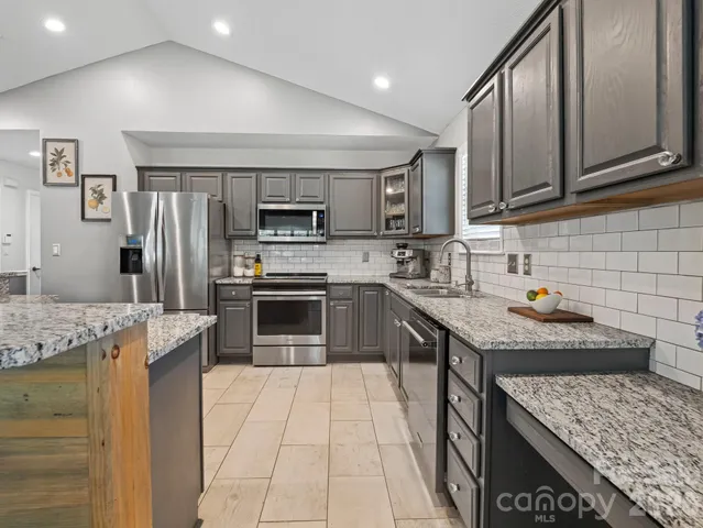 a kitchen with stainless steel appliances granite countertop a sink stove microwave and refrigerator