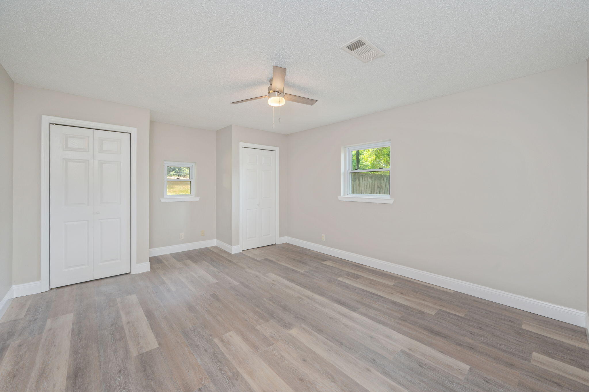 165 Smith Street Crestview, FL 32539 - Photo 13 of 30 an empty room with wooden floor ceiling fan and windows