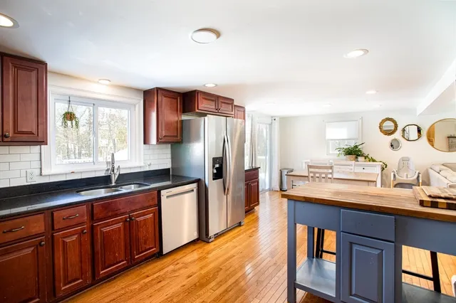 a kitchen with granite countertop a sink stainless steel appliances wooden floor and cabinets