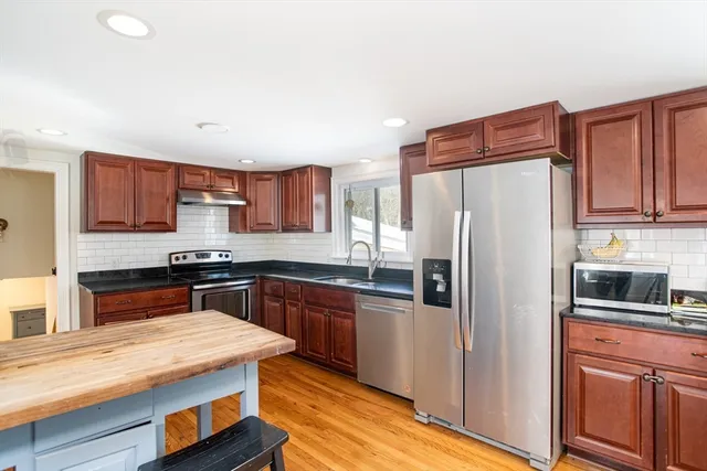 a kitchen with stainless steel appliances granite countertop a refrigerator stove top oven and sink