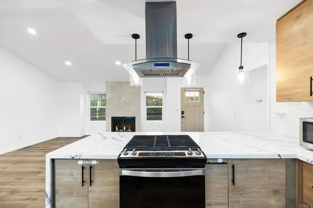 an empty room with wooden floor fireplace and windows