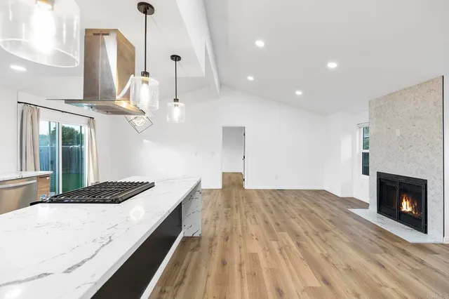 a view of a kitchen with kitchen island stainless steel appliances counter space and wooden floor