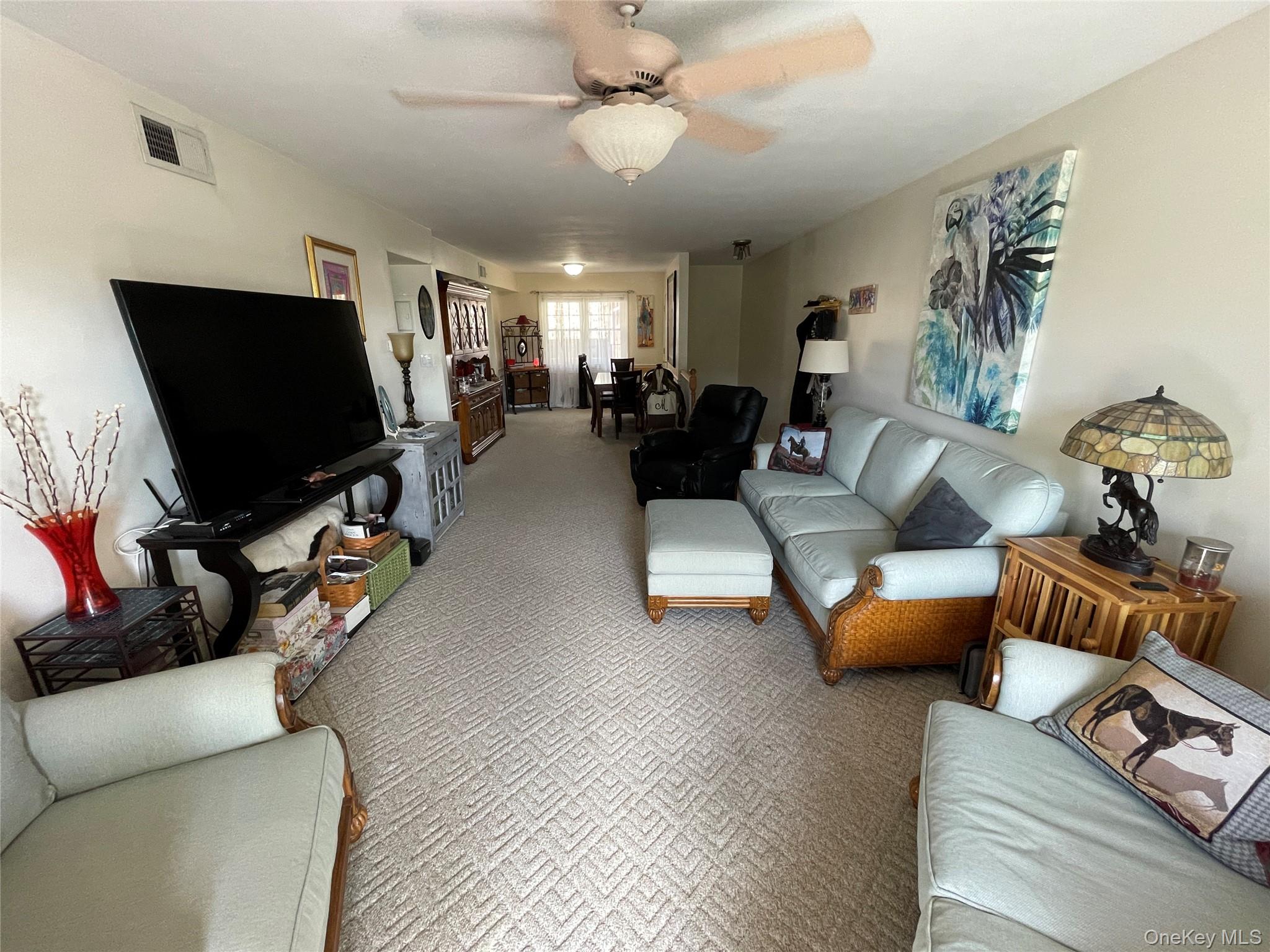 107 Mariners Way Copiague, NY 11726 - Photo 16 of 27 a living room with furniture and a flat screen tv with kitchen view